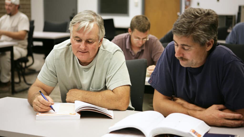 Older men in classroom reading books