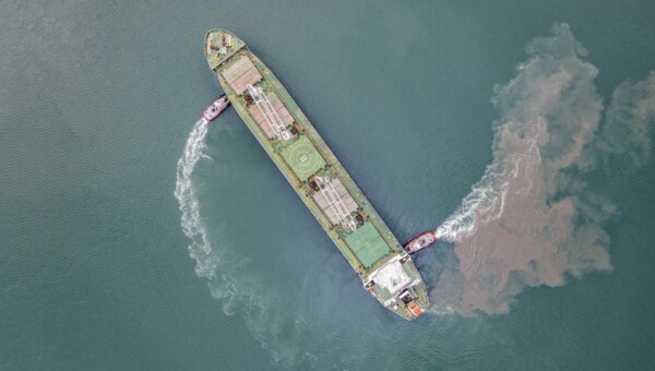 Top view of Freight Ship approaching port with tugboat.